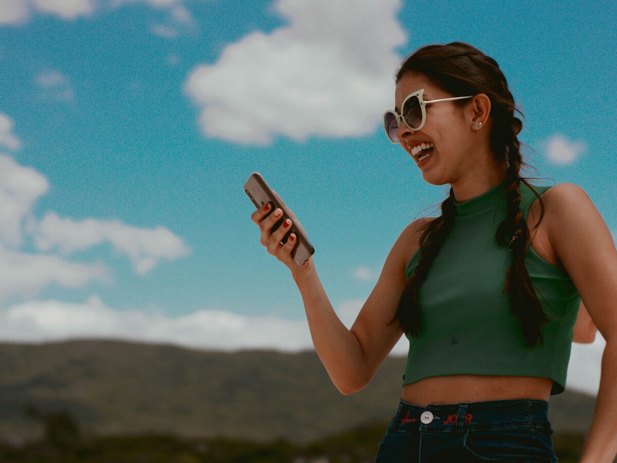 Mulher sorrindo ao ver a resposta no celular
