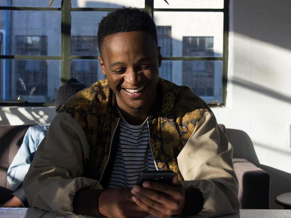 Homem sorrindo ao usar o celular